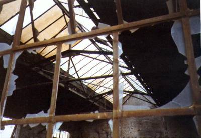Das Innere der kahlen Schmiede, durch Scheibenreste und Stahlverstrebungen fotografiert